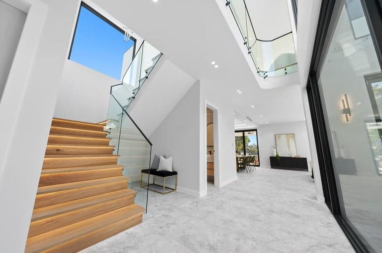 Bright Sydney foyer with stone floors, oak stairs and a glass balustrade