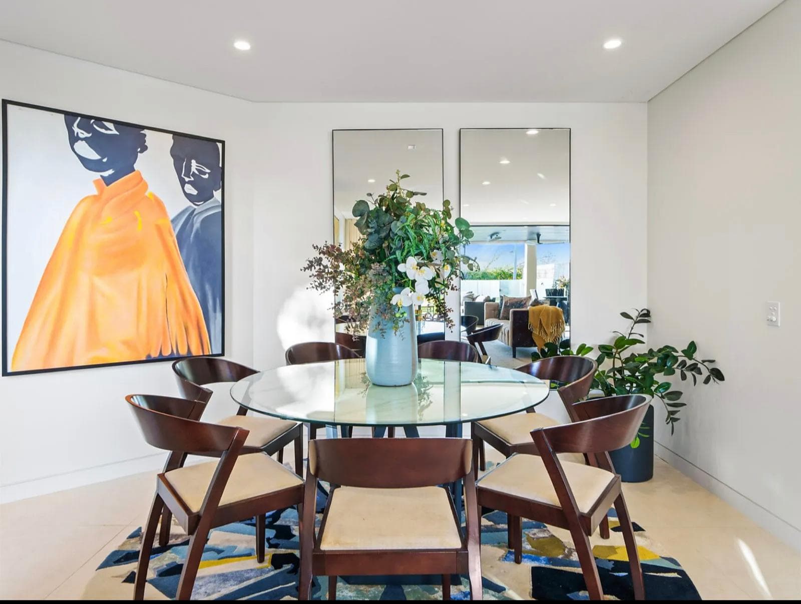 Round glass dining table in a Sydney home with custom joinery and wall mirrors