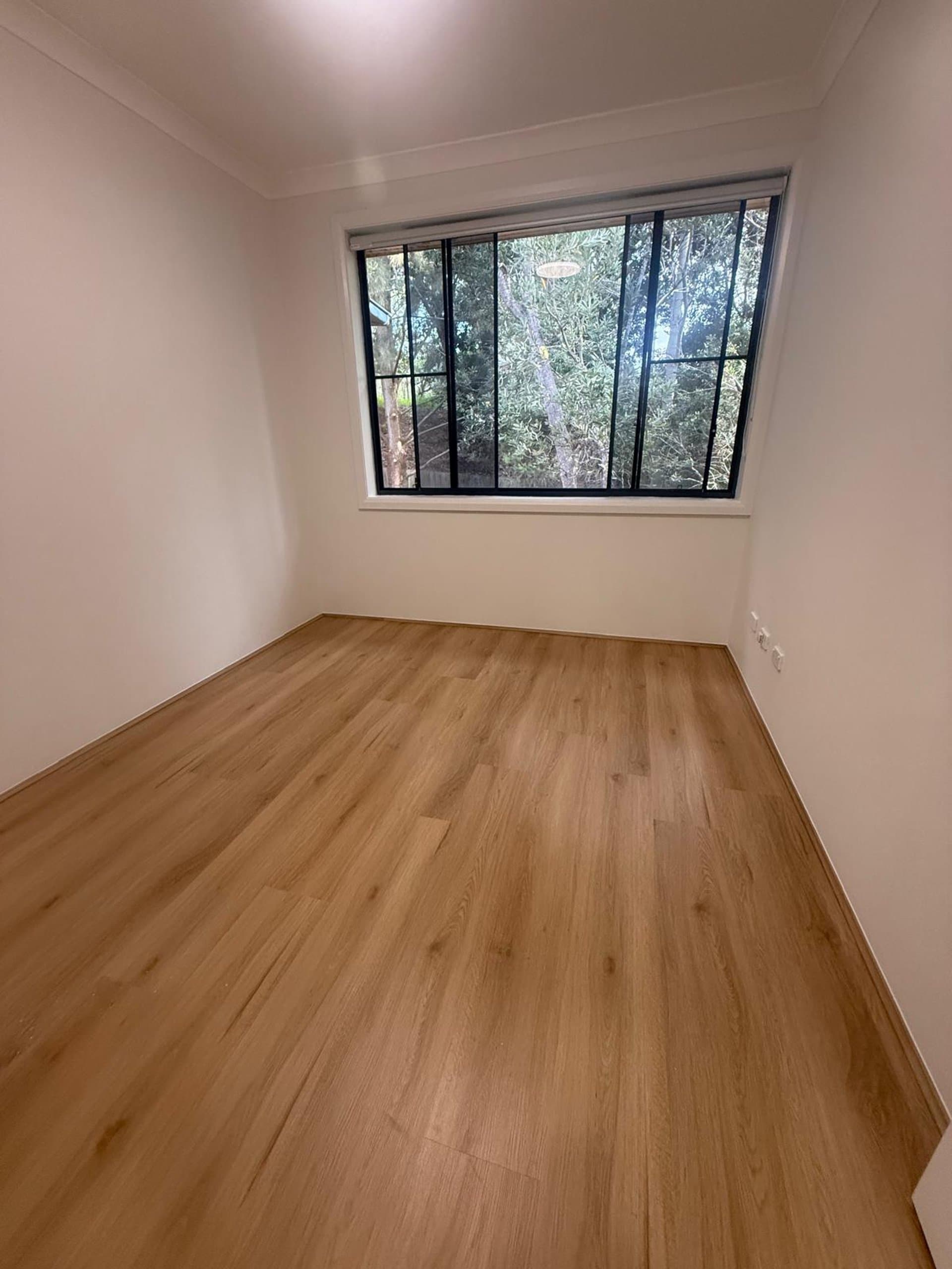 Light oak hybrid flooring in an empty Sydney bedroom with a garden window