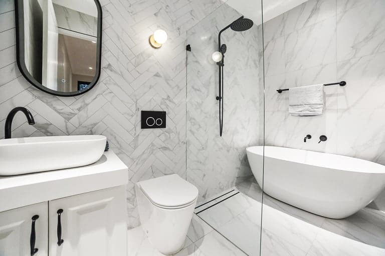 Marble herringbone bathroom in Sydney with black fixtures and a glass wet room