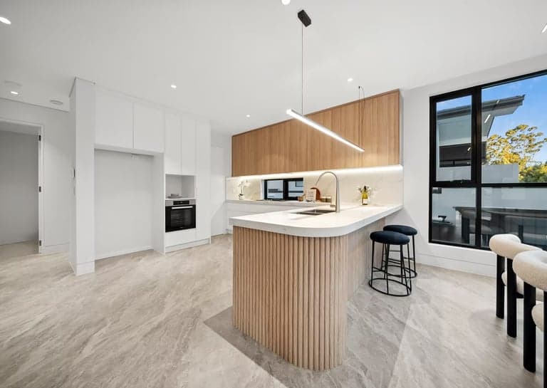 Fluted oak kitchen island with a stone benchtop and linear pendant light in Sydney