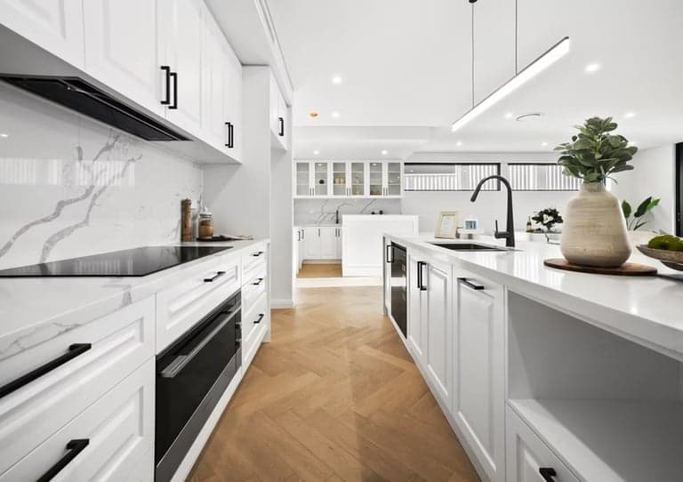 White kitchen renovation in Sydney with herringbone oak floors and a marble splashback