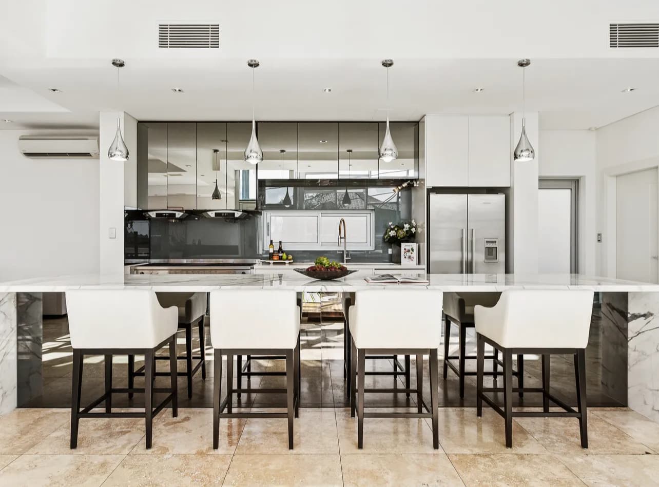 Marble kitchen bar renovation in Sydney with white stools and high-gloss grey cabinets