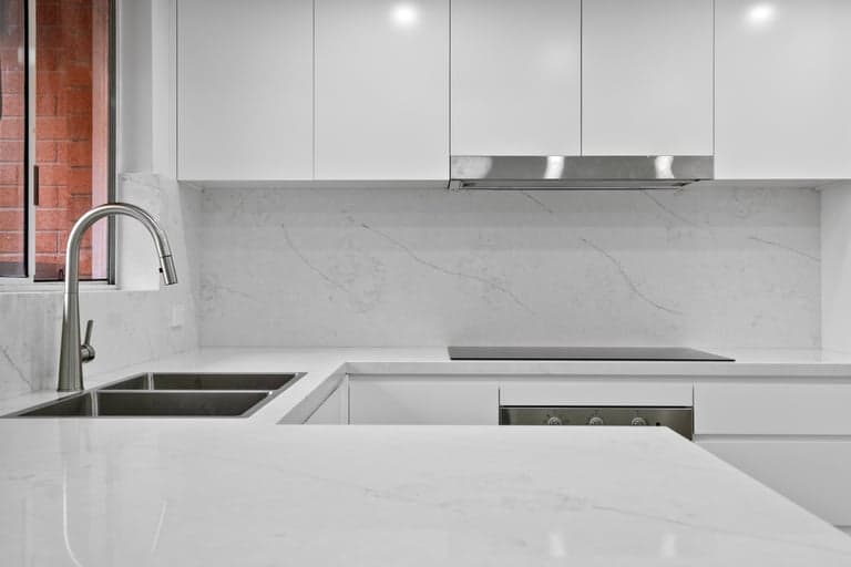 White stone kitchen benchtop in Sydney with a double sink, mixer and induction cooktop
