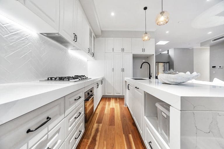 White shaker kitchen renovation in Sydney with a herringbone splashback and timber floors