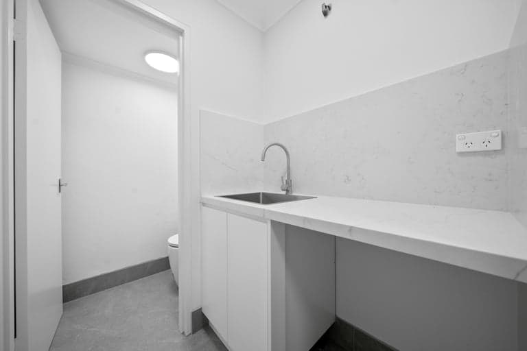 Compact Sydney laundry bench with a stainless sink and custom joinery