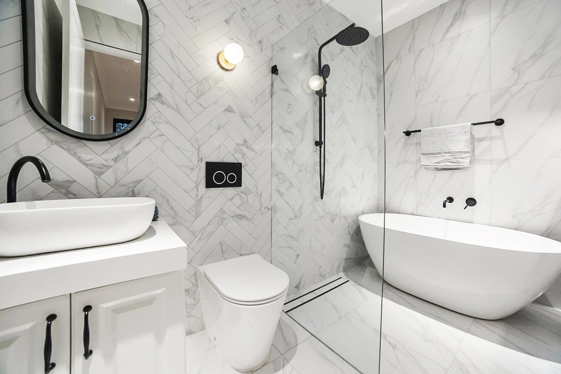 Marble herringbone bathroom in Sydney with black fixtures and a glass wet room
