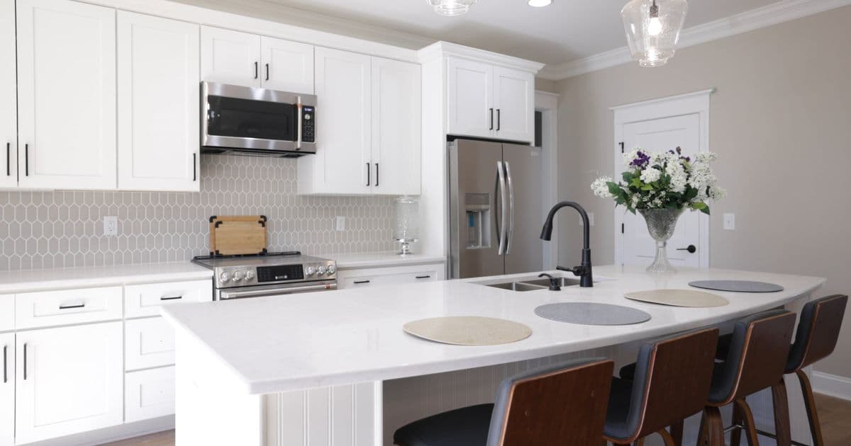 White kitchen renovation with a stone island, timber stools and honeycomb splashback