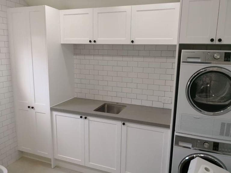 White shaker laundry in Sydney with subway tiles and a stacked washer dryer